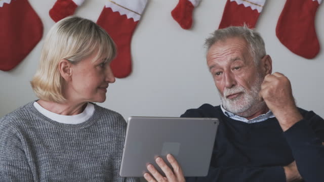 senior-elderly-Caucasian-old-man-and-woman-using-tablet-and-playing-internet-online-together