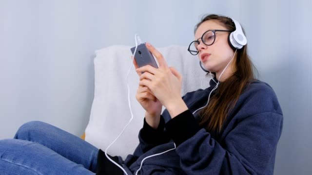 Frau-hört-Musik-in-Kopfhörern-auf-dem-Smartphone-und-singt-ein-Lied.