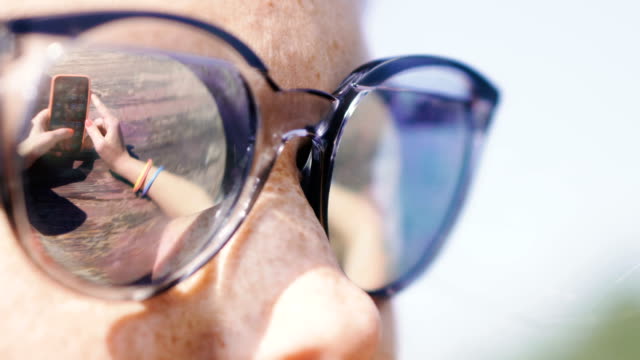 Handy.-Eine-Frau-in-Sonnenbrille-schaut-auf-ein-Handy.