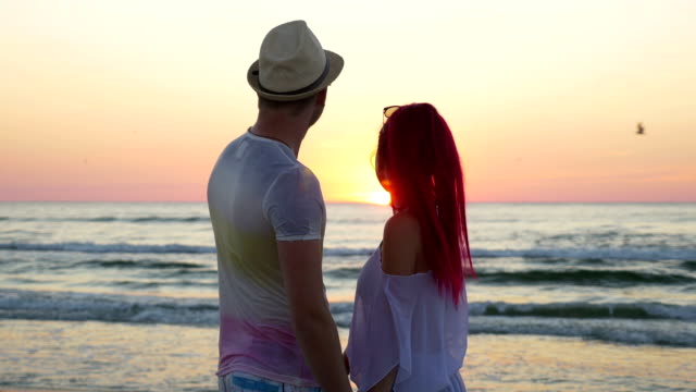 Young-beautiful-couple-watching-an-amazing-sunset-and-kissing-on-beach