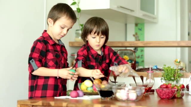 Two-children,-boys,-coloring-easter-eggs-at-home,-eating-strawberries