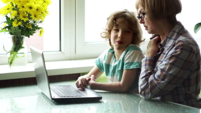 El-niño-en-edad-escolar-más-joven-ayuda-a-la-anciana-a-dominar-la-computadora.