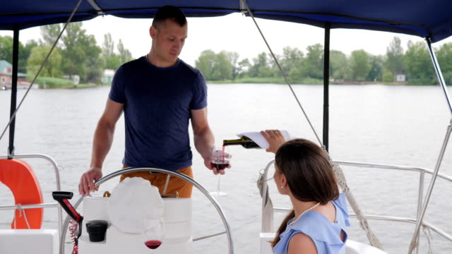 woman-pours-from-bottle-wine,-rest-on-water,-family-couple-drinking-wine-on-yacht,-romantic-couple-drink-red-beverage