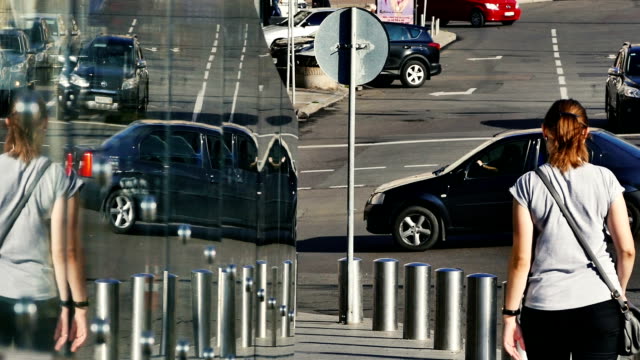 Menschen-und-Autos-bewegen-entlang-einer-Stadtstraße-spiegeln-sich-symmetrisch-in-einer-Glaswand.