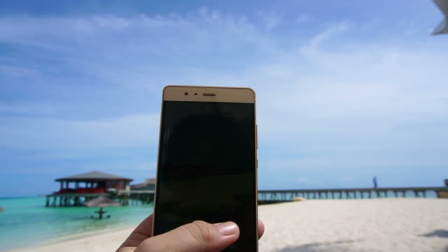 POV-shot-of-a-smart-phone-taking-photo-in-tourist-hand.-Having-fun-at-ocean-vacation