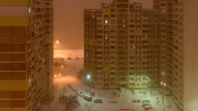 A-snowstorm-in-the-city.-View-from-the-window-to-the-courtyard-at-night.-down-up-timelapse