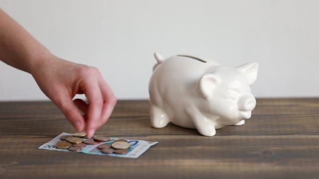 Finance-saving-concept.-Money-throwing-in-the-piggy-bank-euro-coins