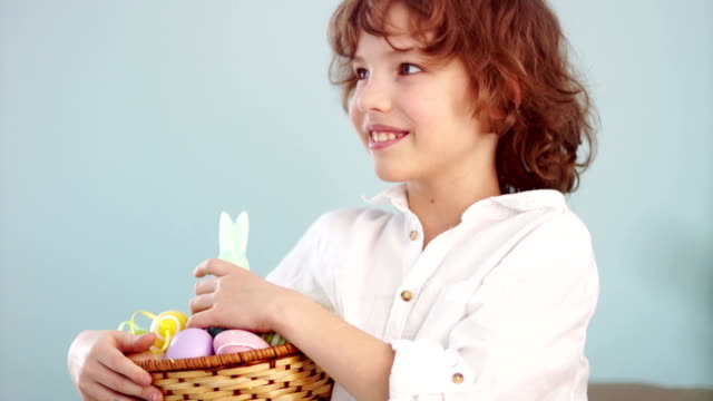 Cheerful-schoolboy-with-a-basket-of-Easter-eggs.-Curly-haired-boy-laughs-fun