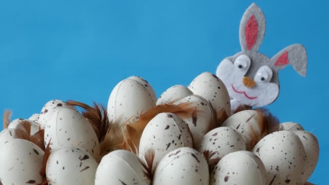 Conejito-de-Pascua-se-esconde-detrás-de-los-huevos-en-el-fondo-azul.