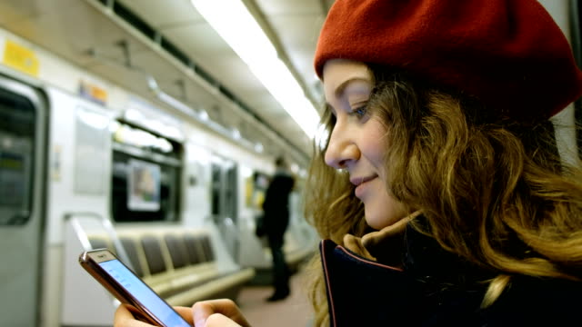 Hermosa-mujer-joven-usa-un-smartphone-en-el-primer-plano-de-metro,-una-chica-imprime-un-mensaje-en-el-teléfono