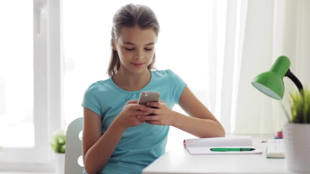 lächelnde-Mädchen-SMS-auf-Smartphone-zu-Hause