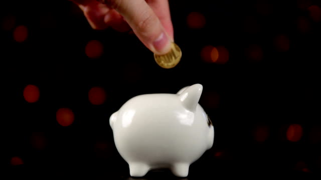 The-concept-of-charity-during-the-movember,-someone-puts-a-coin-in-piggy-bank.