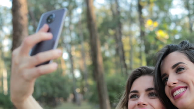 Freundinnen-unter-einem-Selfie-zusammen-mit-Handy-im-park