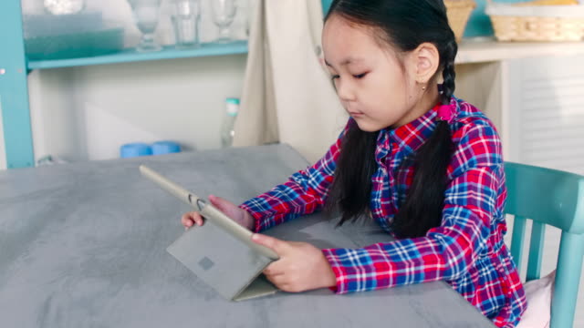 Kleine-Asiatin-mit-Digital-Tablette-zu-Hause