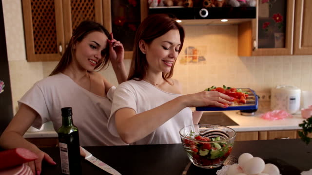 Two-young-beautiful-girls-prepare-a-vegetable-salad-in-the-kitchen.