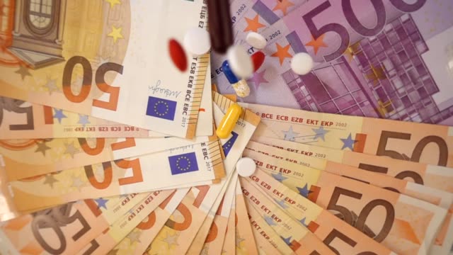 VIDEO,-various-pharmaceutical-drugs-falling-on-euro-banknotes-rotating-below-on-slow-motion