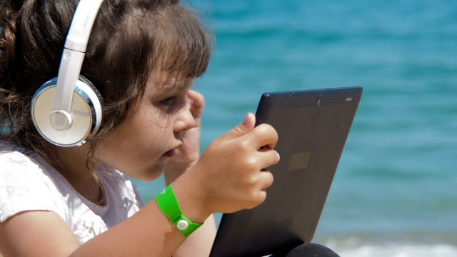 Niño-usando-tableta-en-la-orilla-del-mar.