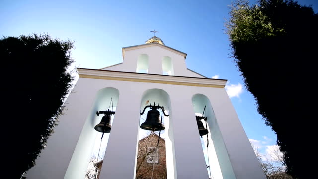 Kirchliche-Glocken-an-einem-Sonnentag-bei-starkem-Wind-Der-Wind-schüttelt-die-Bäume-in-der-Nähe-des-Glockenturms-und-Sonechka-leuchtet-in-der-Zelle-in-der-Nähe-der-Kirchenglocken