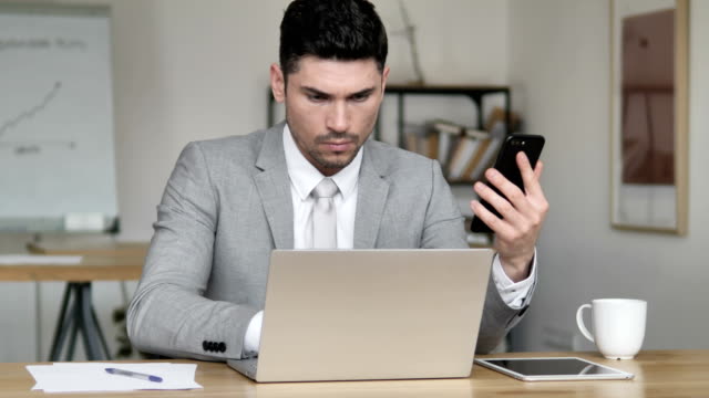 Geschäftsmann-nutzt-Smartphone-und-Laptop