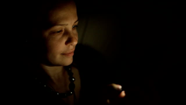 Eine-junge-kaukasische-Frau,-die-nachts-in-einem-Zimmer-auf-der-Couch-mit-einem-Smartphone-sitzt-und-mit-Freunden-in-sozialen-Netzwerken-kommuniziert