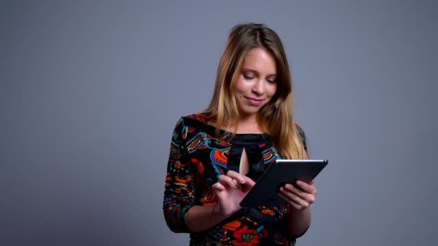 Closeup-portrait-of-attractive-young-caucasian-female-scrolling-on-the-tablet-looking-at-camera-and-laughing