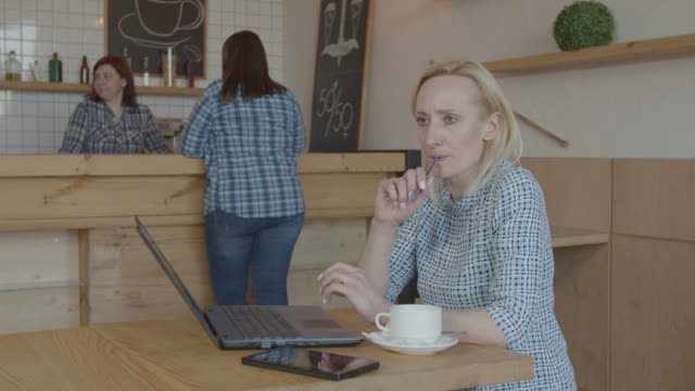 Pensive-female-blogger-working-on-laptop-in-cafe