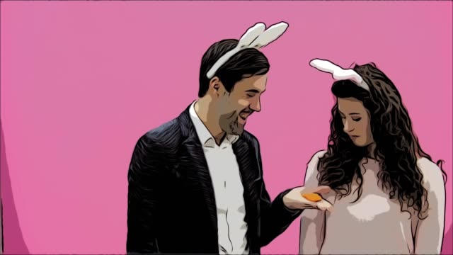 Young-couple-are-beautiful-on-pink-background.-During-this-time,-they-are-dressed-in-rabble-ears.-Looking-at-each-other,-behave-like-rabbits,-reproducing-movements-of-the-mouth-and-teeth.-Easter.