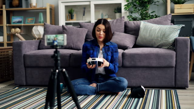 Female-blogger-recording-video-about-modern-headphones-at-home-with-smartphone