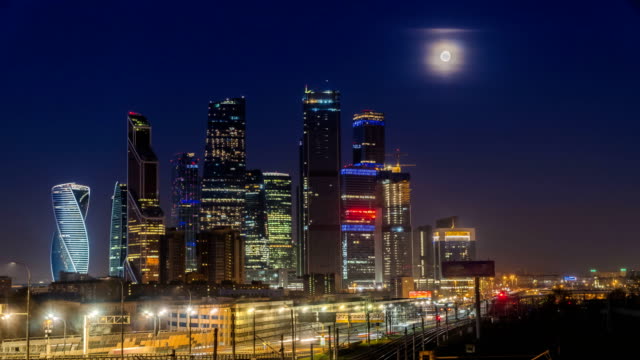 The-moon-rising-over-the-illuminated-highway-and-the-night-city,-time-lapse