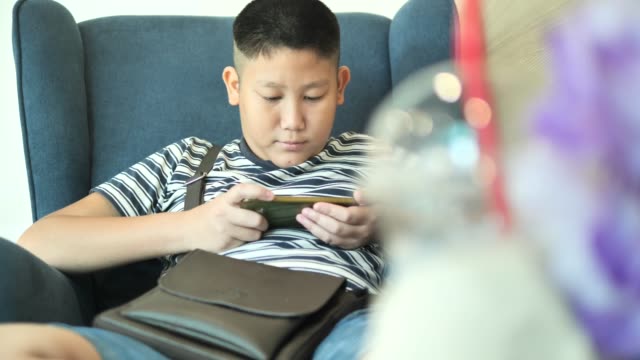 Young-teenager-playing-game-on-smartphone-in-cafe