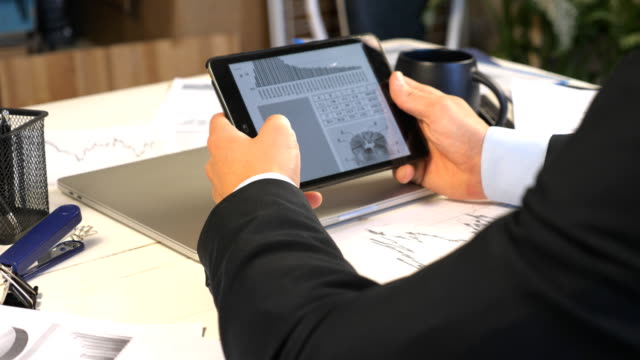 Male-hands-of-young-businessman-developing-a-business-project-and-analyzing-statistical-data-information-on-a-tablet-pc.-Successful-entrepreneur-working-on-modern-digital-device-in-office.-Close-up