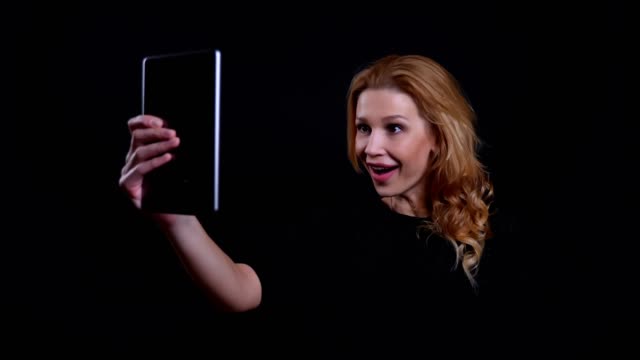 Nahaufnahme-Porträt-von-Erwachsenen-attraktiv-Rothaarige-Frau-mit-einem-Videoanruf-auf-dem-Tablet-mit-Hintergrund-isoliert-auf-schwarz
