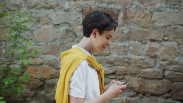 Zeitlupe-des-fröhlichen-Teenagers-mit-modernen-Smartphone-im-Freien