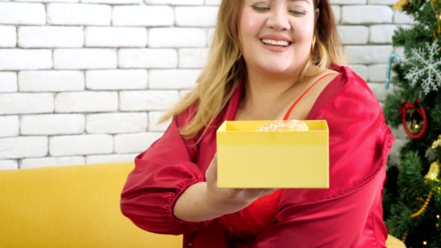 Overweight-woman-receiving-gift-box-with-hamburger-on-christmas's-day