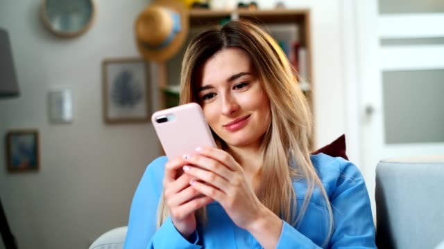 Portrait-of-women-holding-cell-pink-telephone,-girl-texting-using-app-and-watching-video-on-mobile-phone,-enjoying-reading-social-media-at-home