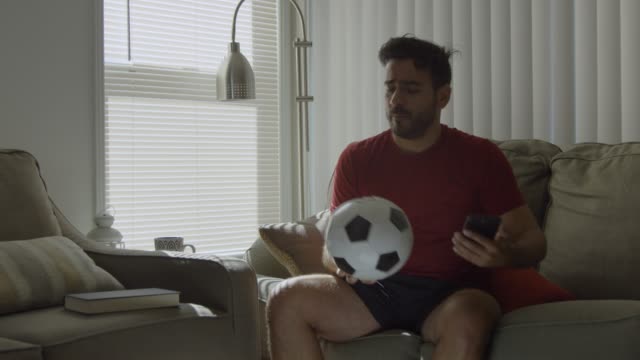 Cámara-lenta-de-los-aficionados-al-fútbol-besando-una-pelota-de-fútbol-y-sosteniendo-el-teléfono-móvil