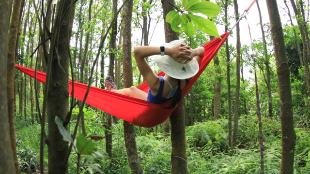 Mujer-relajándose-en-hamaca-con-teléfono-inteligente-en-la-selva-tropical,4k