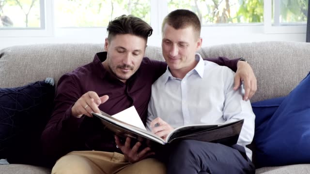 Gay-couple-relaxing-on-couch,-reading-book.