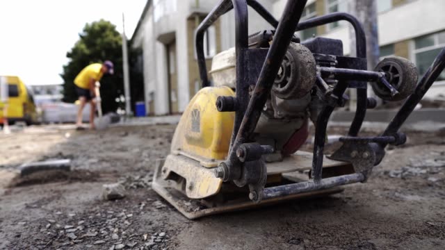 Vibrational-paving-stone-machine-for-finish-on-a-sidewalk-road-construction-site-staying-on-a-ground-and-stones-during-sidewalk-construction-works.