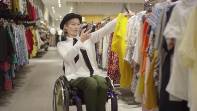 Hermosa-mujer-en-silla-de-ruedas-fotografiando-blusa-en-la-tienda-de-ropa