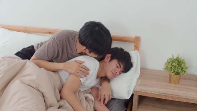 Pareja-gay-asiática-besa-y-abraza-en-la-cama-en-casa.-Jóvenes-asiáticos-LGBTQ-hombres-feliz-descanso-juntos-pasar-tiempo-romántico-después-de-despertar-en-el-dormitorio-en-casa-en-el-concepto-de-la-mañana.-Disparo-a-cámara-lenta.