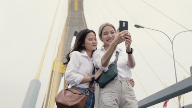 Glückliche-asiatische-lesbische-Paare-mit-Smartphone-Selfie-genießen-Reisen-in-Thailand.-Schöne-junge-Frauen-mit-Spaß-in-der-Ferienzeit.-LGBT-Konzept.