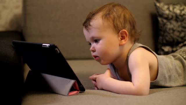 Niña-pequeña-seria-y-solitaria-niña-sentada-y-mirando-en-la-tableta-portátil