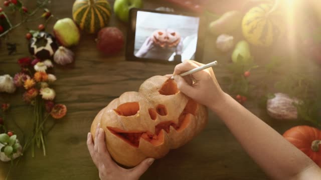 Mujer-talla-una-calabaza-decoración-de-Halloween-con-manual-de-tableta