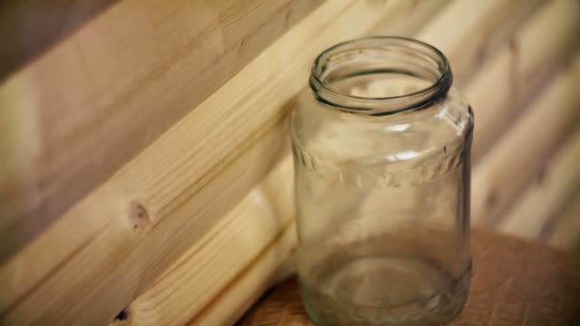 Pfennige-Droped-in-einem-transparenten-Glas-auf-hölzernen-Hintergrund