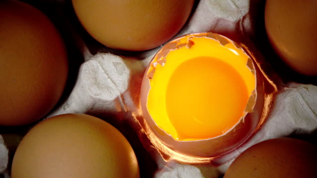 Huevos-yacen-en-el-soporte-de-cartón,-un-huevo-roto