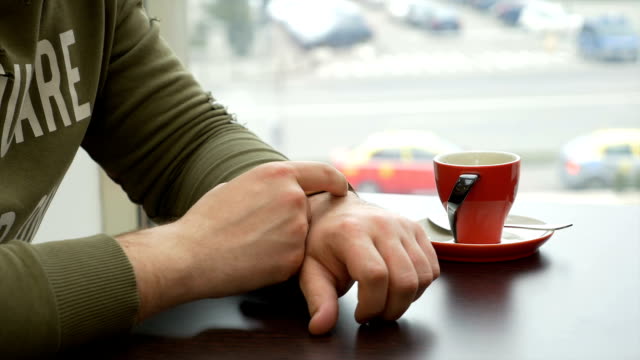 Mann-mit-Smartwatch-im-Kaffeehaus-in-der-Stadt