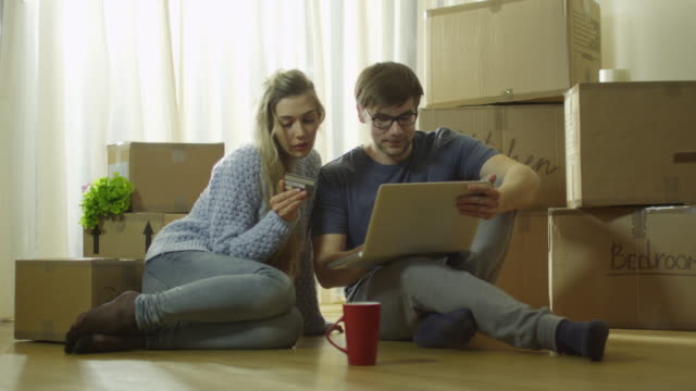 Joven-pareja-está-utilizando-el-ordenador-portátil-para-compras-en-línea-en-nueva-casa.-Filmada-en-RED-Cinema-Camera-en-4K-(UHD).