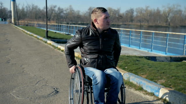 Krüppel-reitet-auf-Brücke-in-der-Nähe-von-River-am-Rollstuhl,-Porträt-auf-männliche