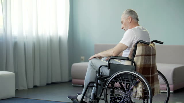 Triste-triste-solitario-anciano-sentado-en-silla-de-ruedas-en-su-sala-de-casa-de-enfermería